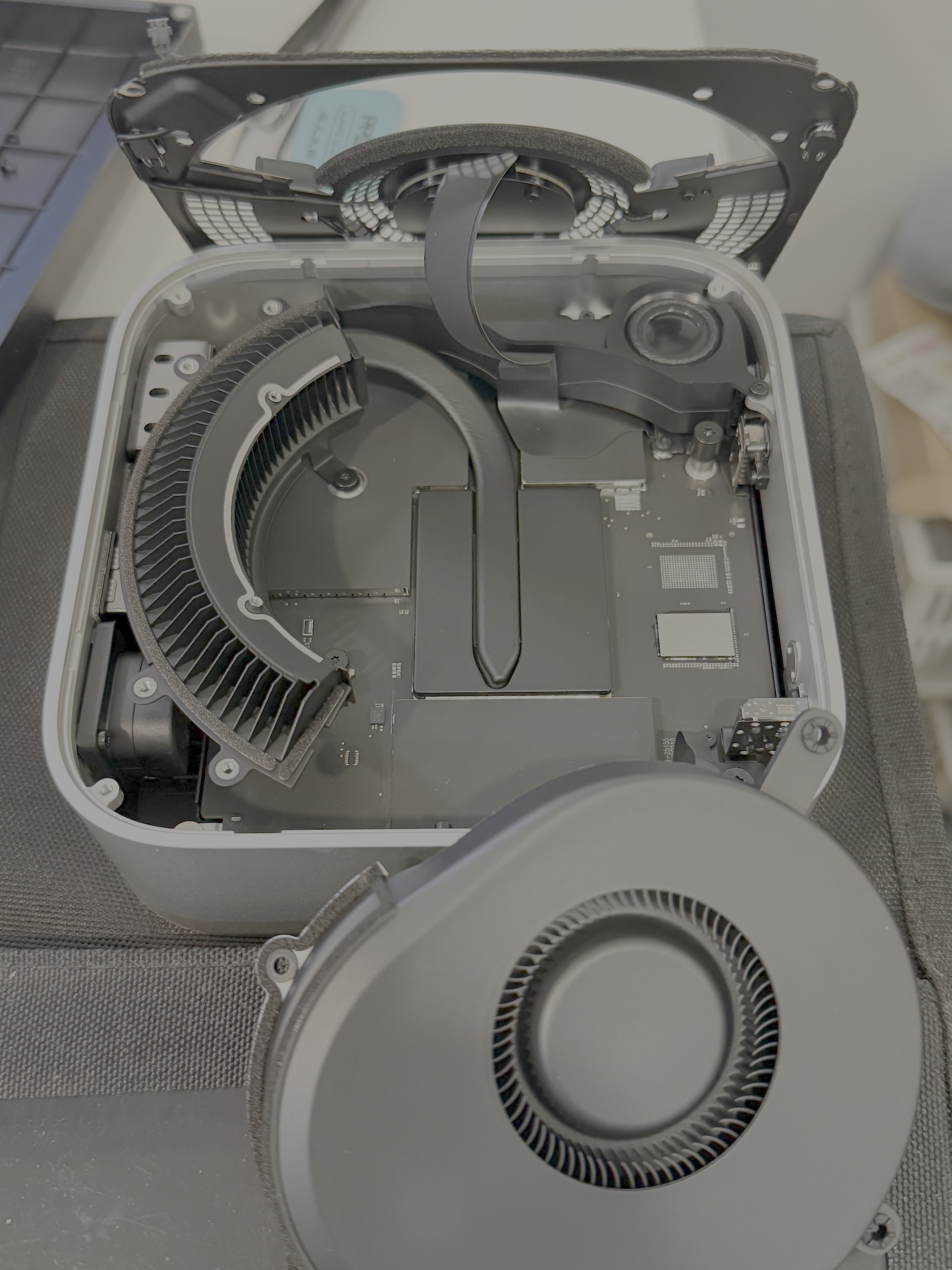 M6 Mac mini 拆開底蓋與風扇後的機內全景：主機板中央的散熱片與周邊元件