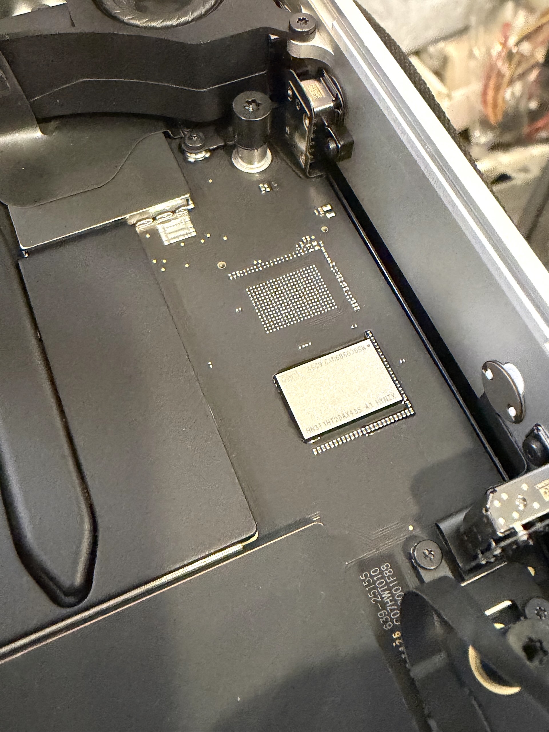 M6 Mac mini 主機板特寫：SK hynix NAND 快閃記憶體顆粒直接焊在主機板上，旁邊是一塊未上件的 BGA 焊點